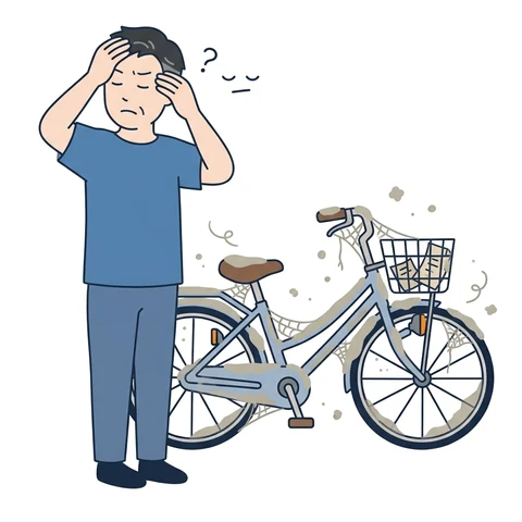 ほこりをかぶった自転車の横で頭を抱える男性